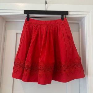 Description: Alice + Olivia - Red Short Skirt with Lace Trim Detail.